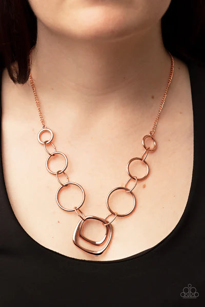 Paparazzi Accessories Linked Up Luminosity - Copper A mismatched collection of shiny copper rings and asymmetrical shiny copper hoops delicately links below the collar, resulting in a modern industrial display. Features an adjustable clasp closure. Neckla
