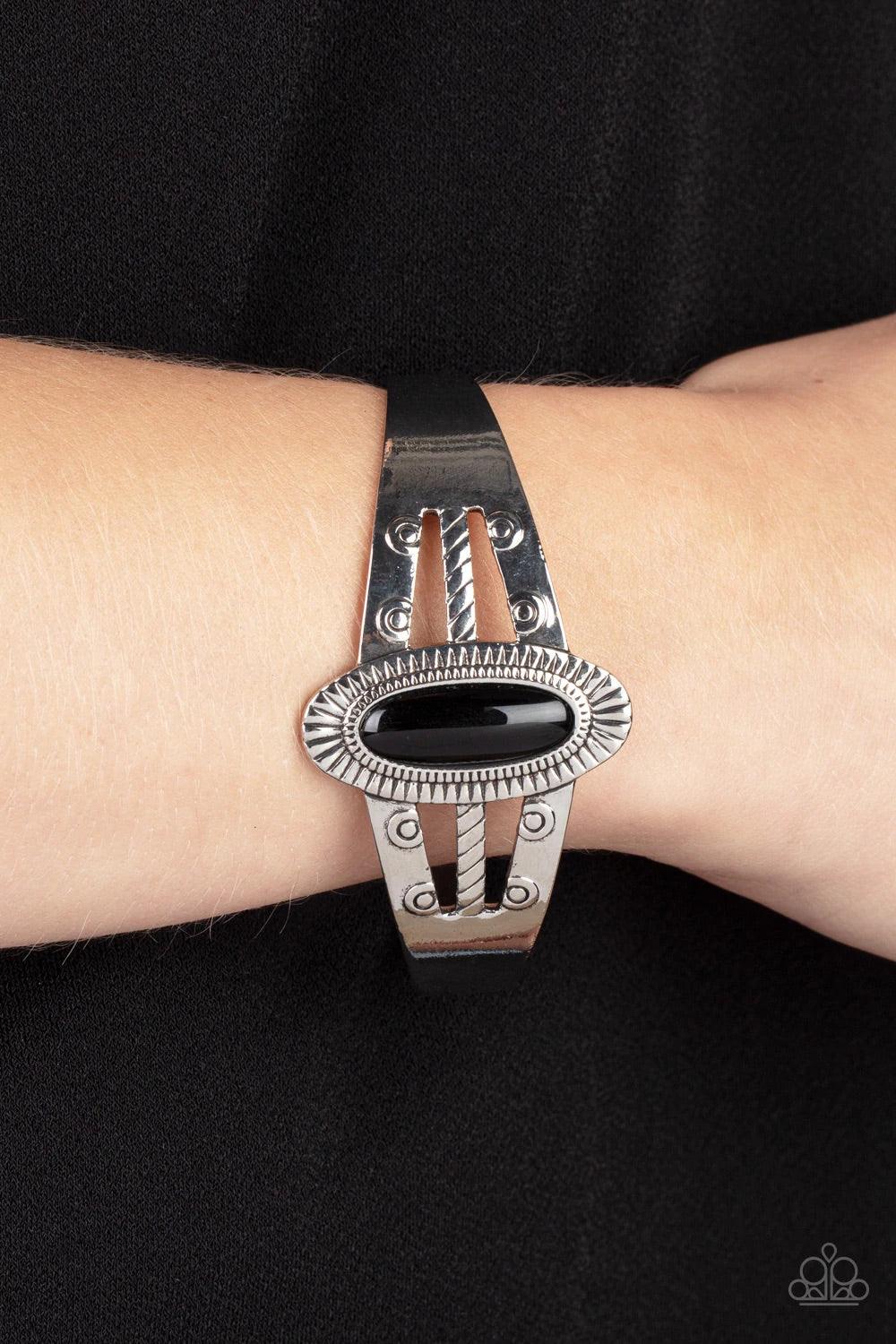 Paparazzi Accessories Wanderlust Walkabout - Black An oval black bead is pressed into the center of a textured silver frame atop a layered silver cuff stamped in swirly texture, resulting in a trendy pop of color around the wrist. Sold as one individual b