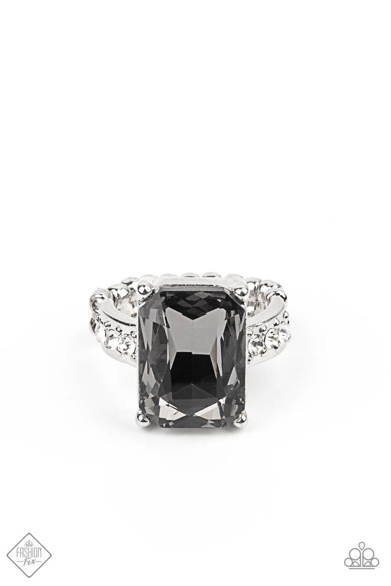 Paparazzi Accessories Bring Down the POWERHOUSE - Silver Featuring an elegant emerald-style cut, an oversized smoky gem is pressed into the center of a dainty silver band dotted in glassy white rhinestones, resulting in some serious show-stopping sparkle.