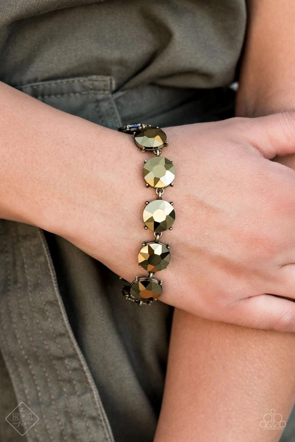 Paparazzi Accessories Fabulously Flashy ~Brass Nestled inside classic brass fittings, a collection of oversized aurum rhinestones delicately links around the wrist for a flashy finish. Features an adjustable clasp closure. Sold as one individual. Jewelry