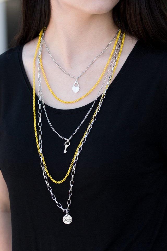 Paparazzi Accessories Right on Key - Yellow Layers of yellow and silver chain fall together to create the illusion of five separate necklaces. Each silver chain is adorned with a small silver charm, including a heart and a key. Features an adjustable clas