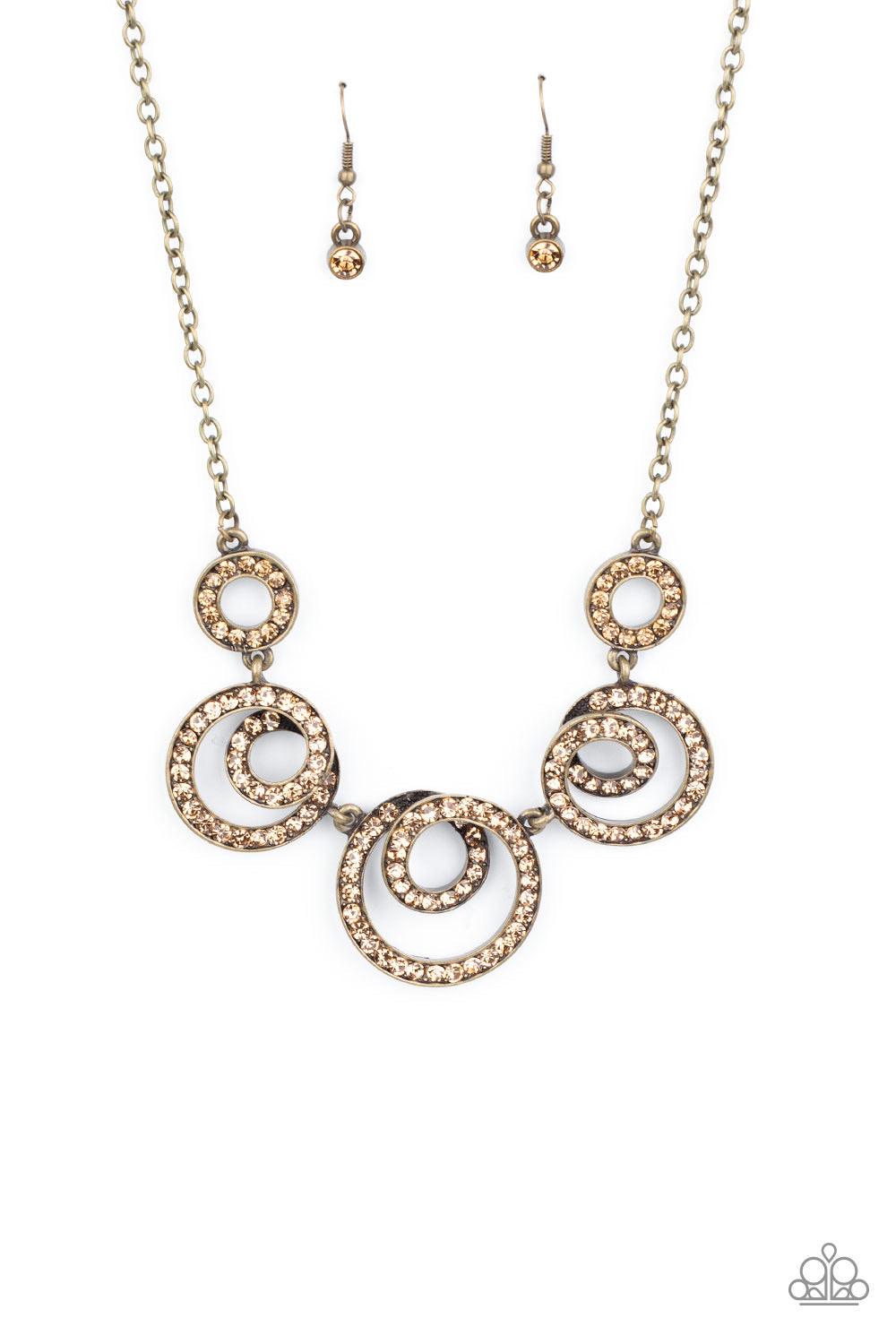 Paparazzi Accessories Total Head-Turner - Brass Encrusted in glassy topaz rhinestones, swirling brass frames delicately connect below the collar for a statement-making finish. Features an adjustable clasp closure. Sold as one individual necklace. Includes