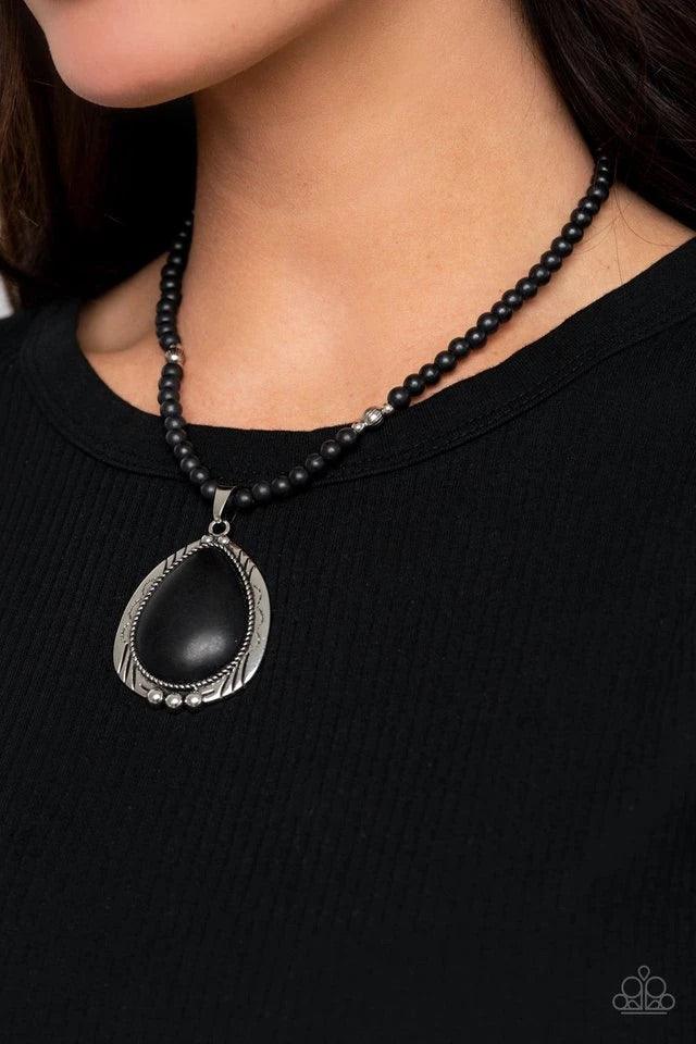 Paparazzi Accessories Evolution - Black An oversized black stone teardrop is pressed into the center of an ornate silver frame that is studded and stamped in tribal inspired patterns. The rustic pendant glides along an earthy strand of black stone and ant