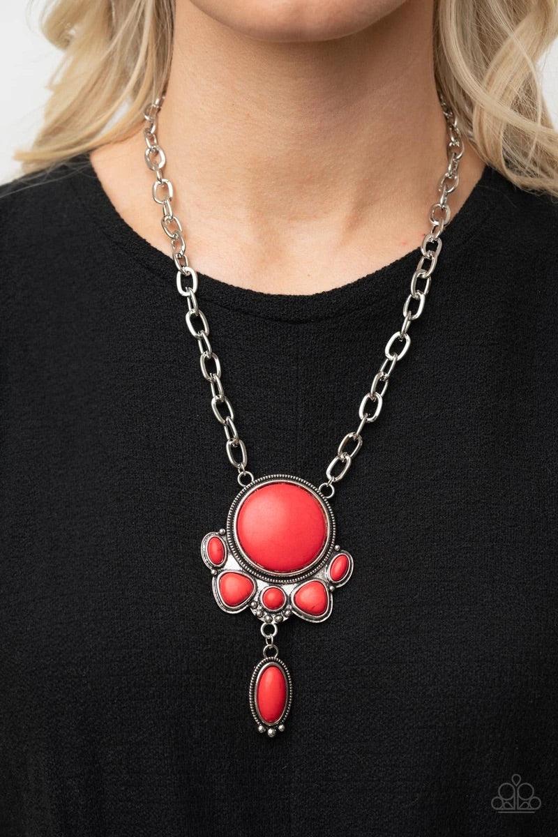 Paparazzi Accessories Geographically Gorgeous - Red A large red stone encased in a studded silver frame swings dramatically from a heavy silver chain with oversized links. A collection of red stones wraps around the bottom of the large pendant, with an el