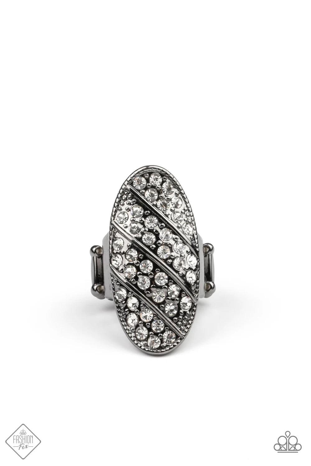 Paparazzi Accessories Galactic Glitz - Black Rows of glassy white rhinestones slant across a stretched oval frame dotted in gunmetal studs, creating a dramatic centerpiece atop the finger. Features a stretchy band for a flexible fit.Sold as one individual