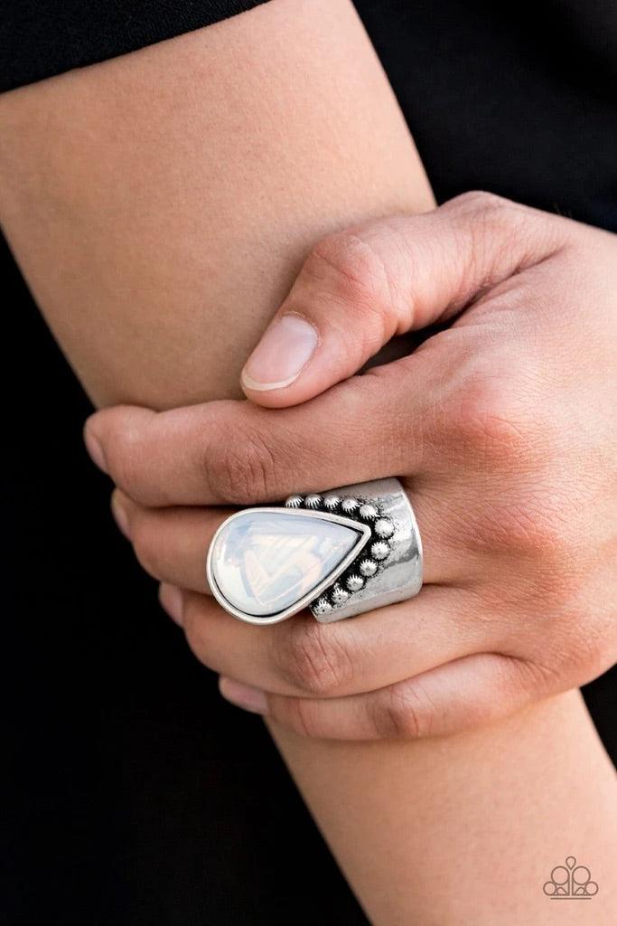 Paparazzi Accessories Opal Mist - White Featuring a milky iridescence, the tip of a glassy white teardrop attaches to a studded silver band. The bottom of the ethereal teardrop drips down towards the knuckle, creating a bold, one-of-a-kind statement piece