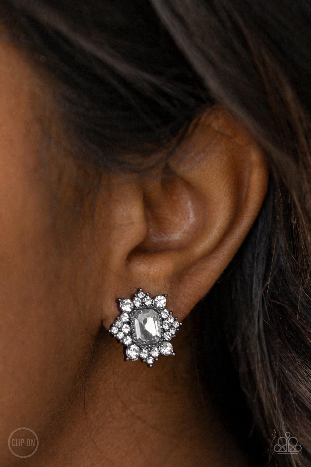 Paparazzi Accessories Interstellar Sparkle - Black *Clip-on Featuring sleek gunmetal fittings, dainty white rhinestones coalesce around a glittery white emerald style rhinestone center for a stellar look. Earring attaches to a standard clip-on fitting. Je