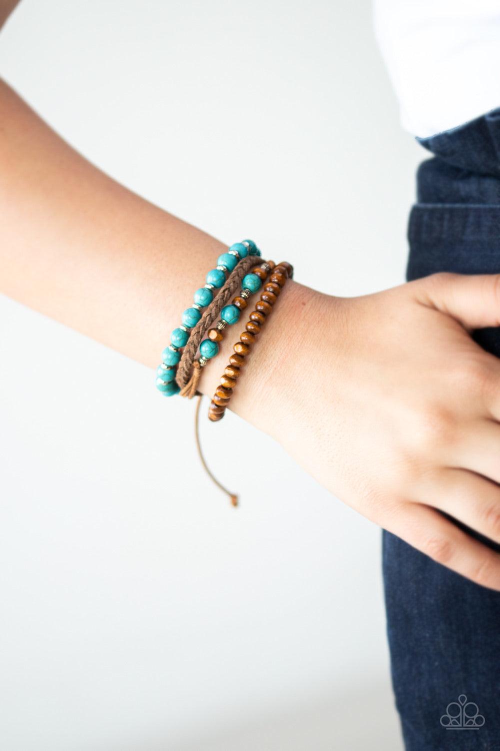 Paparazzi Accessories Renewable Energy - Blue Featuring turquoise stones, dainty silver accents, and earthy wooden beads, mismatched strands of brown cording and braided suede bracelets stack across the wrist for an earthy look. Features an adjustable sli