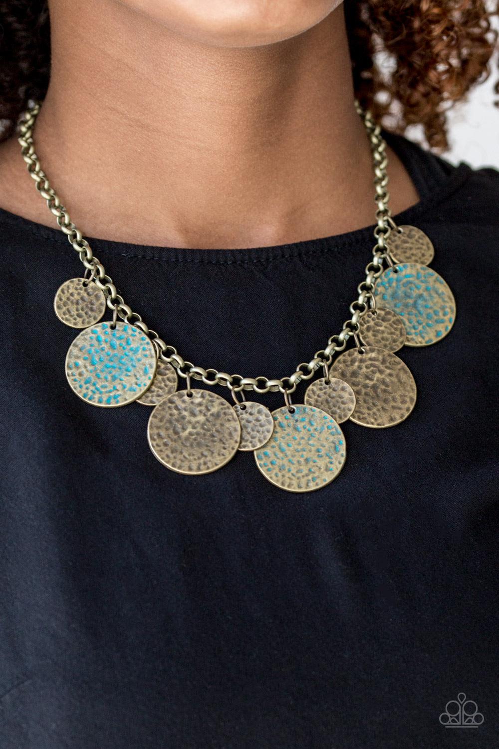 Paparazzi Accessories Treasure HUNTRESS - Brass Delicately hammered in antiqued textures, small and large brass discs alternate below the collar. Three brass discs are brushed in a patina finish for a colorful rustic finish. Features an adjustable clasp c