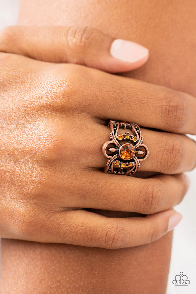 Paparazzi Accessories We Wear Crowns Here - Copper A solitaire topaz rhinestone is flanked by stacked rows of dainty topaz rhinestones inside swooping copper bars dotted in antiqued copper studs, resulting in a refined sparkle atop the finger. Features a