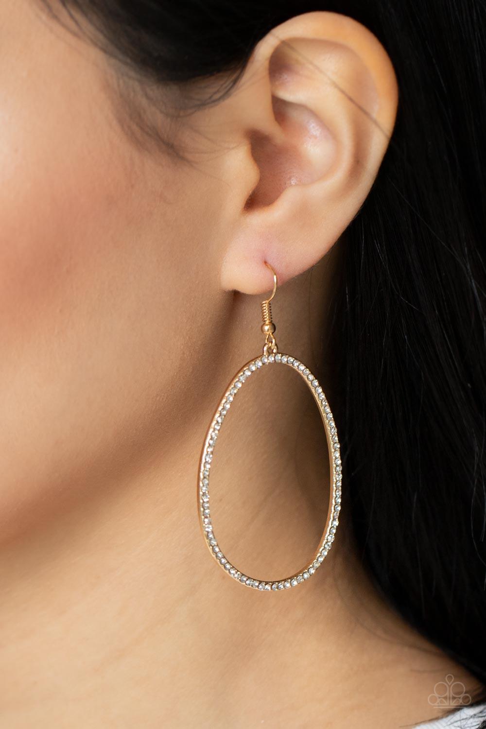Paparazzi Accessories OVAL-ruled - Gold Dotted in dainty white rhinestones, an asymmetrical oval gold frame swings from the ear for a sassy look. Earring attaches to a standard fishhook fitting. Sold as one pair of earrings. Jewelry