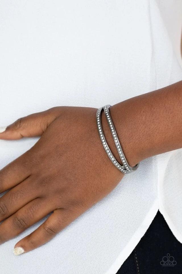 Paparazzi Accessories A Show of FIERCE - Black Encrusted in glassy white rhinestones, an oval gunmetal frame attaches to a matching shiny frame, creating a timelessly layered bangle-like cuff around the wrist. Features a hinged closure. Jewelry