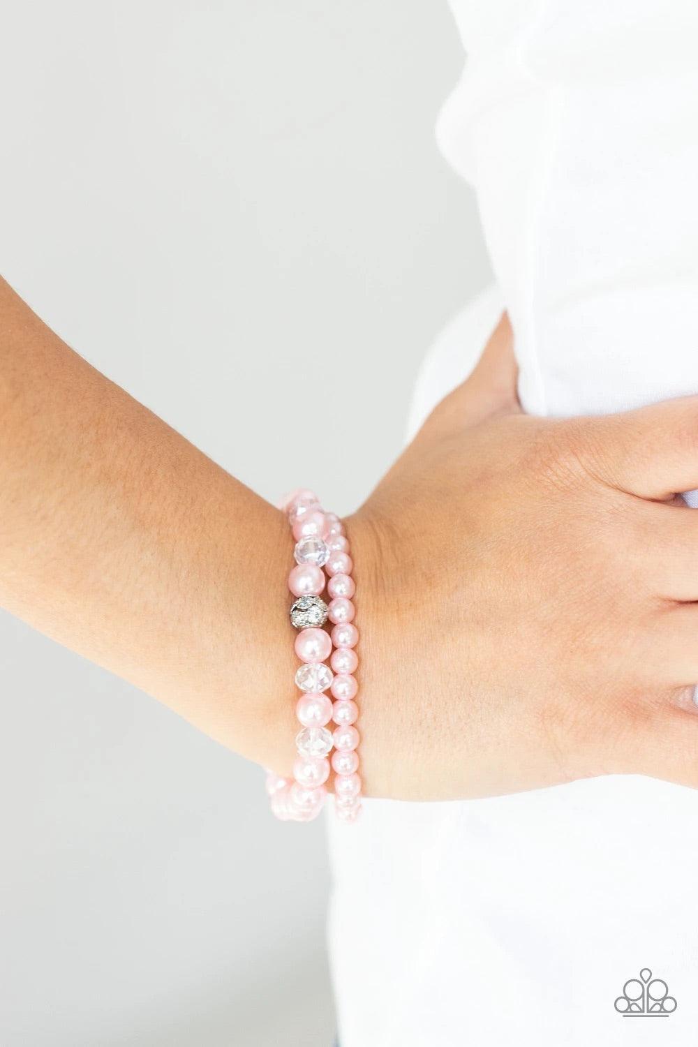Paparazzi Accessories Cotton Candy Dreams - Pink A collection of dainty pink pearls and glassy crystal-like beads are threaded along two stretchy bands around the wrist, creating timeless layers. A white rhinestone encrusted silver bead adorns the center