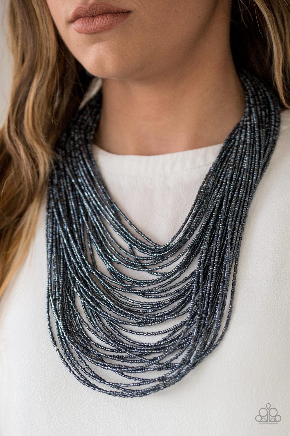 Paparazzi Accessories Ice Storm - Blue Brushed in an icy metallic shimmer, countless strands of blue seed beads drape across the chest in a bold fashion. Featuring a collision of shapes and shimmer, the glittery strands connect to two large silver accents
