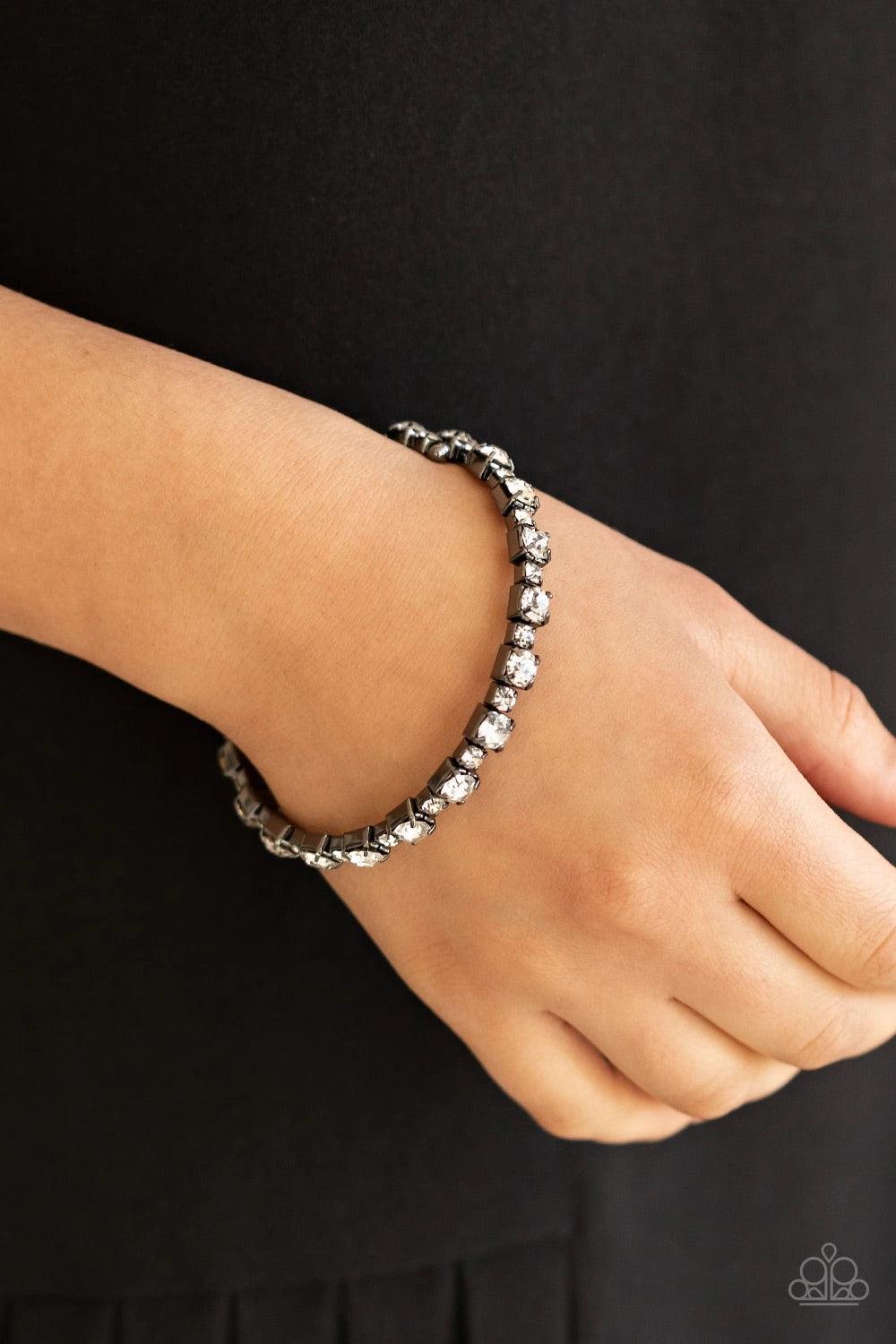 Paparazzi Accessories Photo Op - Black Featuring gunmetal square fittings, dainty and classic white rhinestones delicately alternate along a flexible wire, coiling into a glamorous centerpiece around the wrist. Jewelry