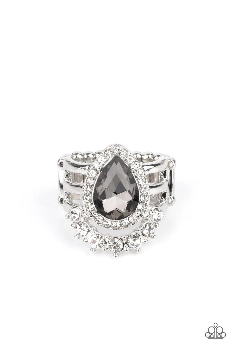Paparazzi Accessories Elegantly Cosmopolitan - Silver An elegantly oversized smoky teardrop gem, encompassed in a dainty rhinestone frame, sits atop three airy silver bars. A row of classic white rhinestones curves beneath the gem for a glamorous finish.