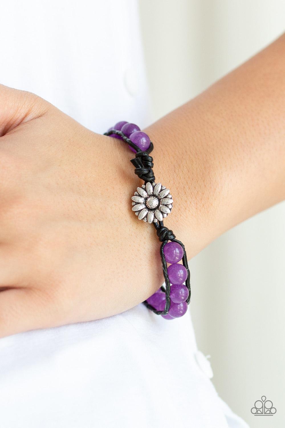 Paparazzi Accessories Daisy Guru - Purple Featuring a silver floral fitting, a collection of glassy purple stones are threaded between two strands of black cording around the wrist for a seasonal flair. Features a button loop closure. Jewelry