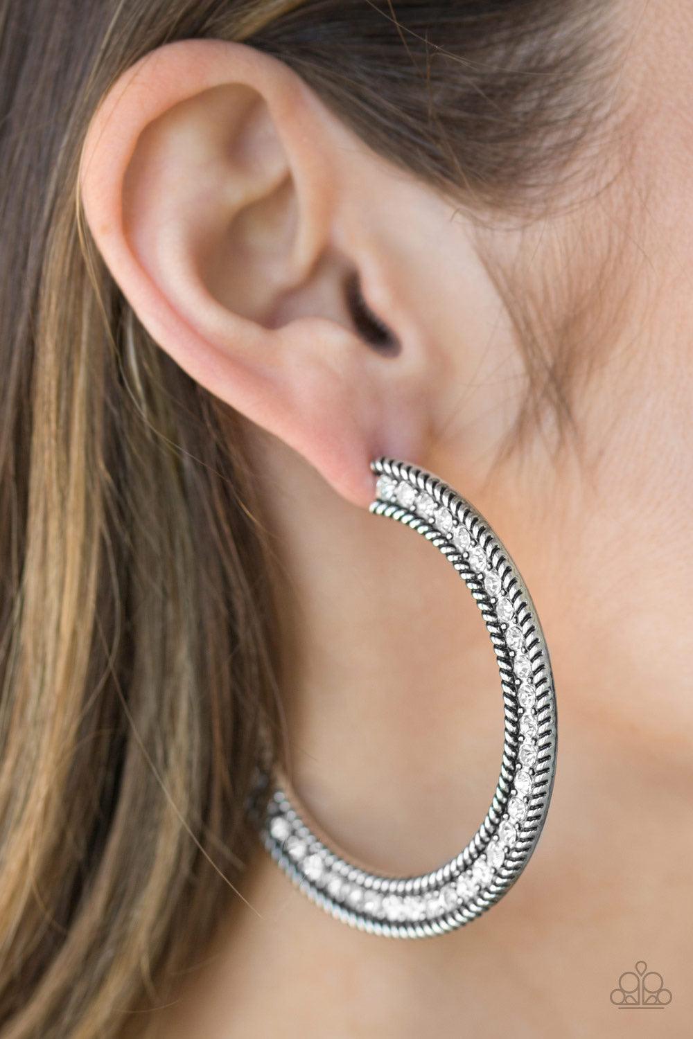 Paparazzi Accessories HAUTE Mama - White Glittery white rhinestones are encrusted along the front of a textured silver hoop for a sassy finish. Earring attaches to a standard post fitting. Hoop measures 2 1/4" in diameter. Sold as one pair of hoop earring