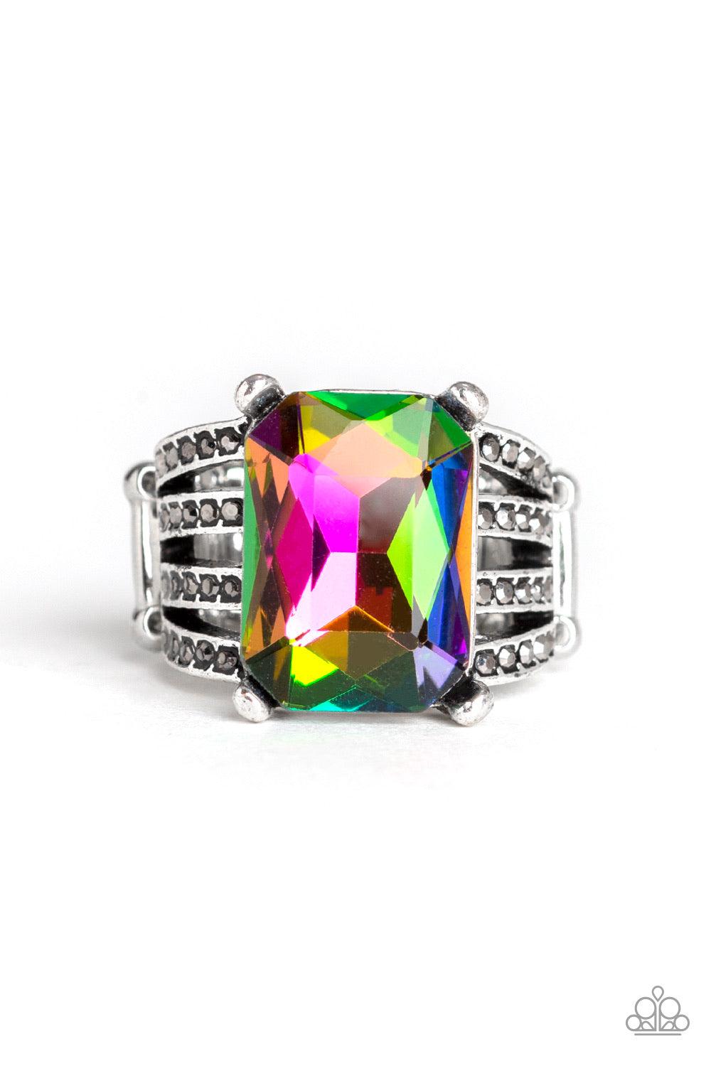 Paparazzi Accessories Expect Heavy REIGN - Multi Featuring a regal emerald style cut, an oversized rainbow gem is pressed into the center of stacked silver bands radiating with dainty hematite rhinestones for a dramatic look. Features a stretchy band for