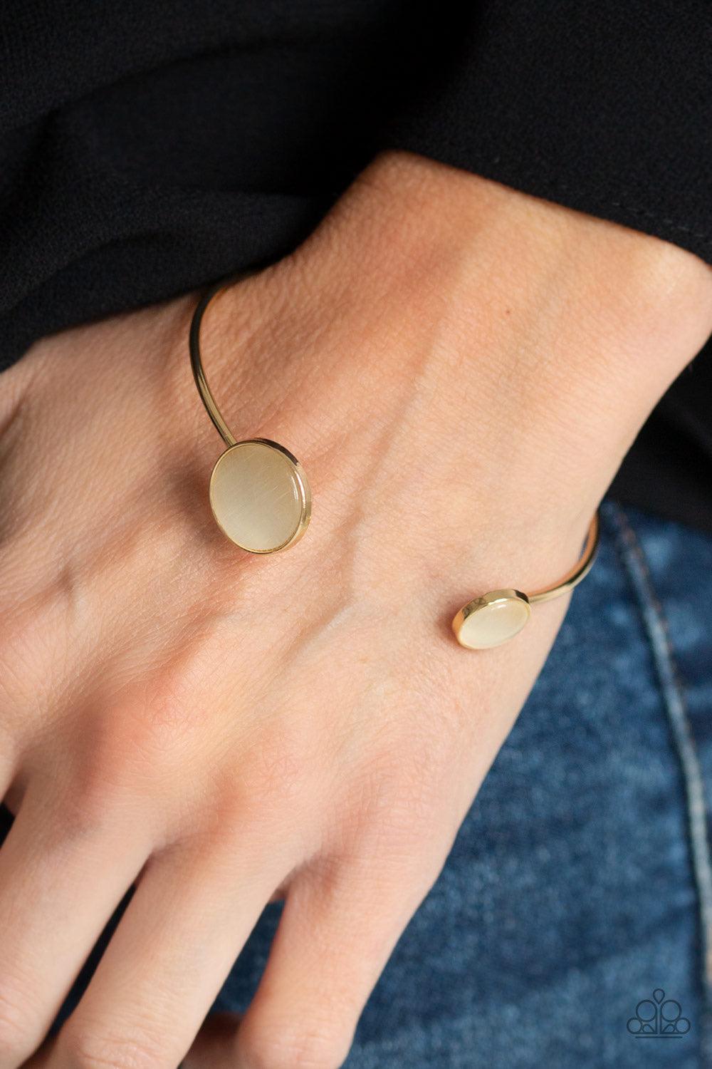 Paparazzi Accessories Brilliantly Basic - Gold Featuring glowing cat's eye stone fittings, a wire-like gold bar curls around the wrist, creating a dainty cuff. Jewelry