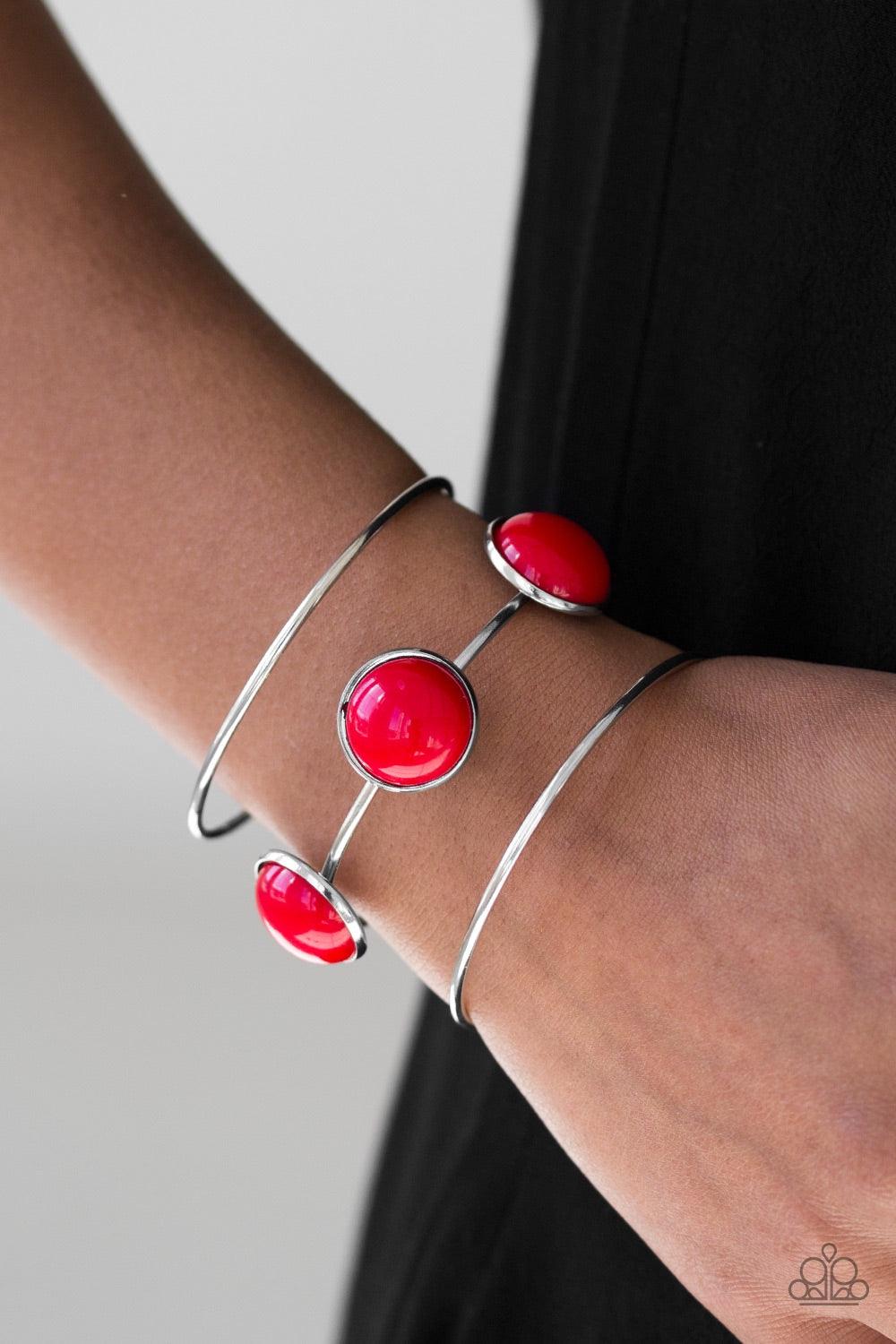 Paparazzi Accessories Lush Lagoon - Red Three shimmery silver bars arc across the wrist, coalescing into an airy cuff. Three fiery red beads are pressed into the centermost bar for a bubbly finish. Jewelry