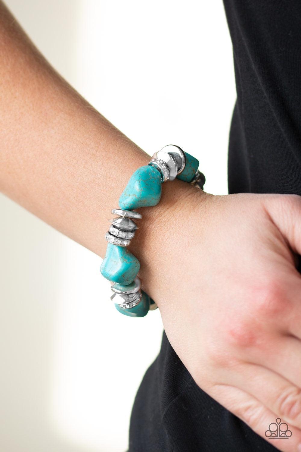 Paparazzi Accessories Stone Age Stunner - Blue A collection of refreshing turquoise stones, shimmery silver accents, and white rhinestone encrusted rings are threaded along a stretchy band around the wrist for a seasonal look. Jewelry