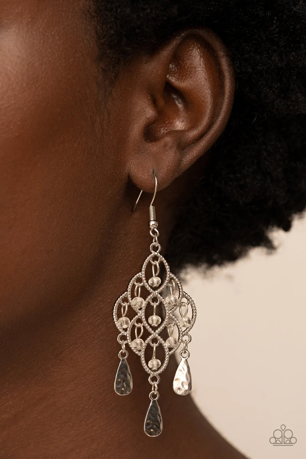 Paparazzi Accessories Sentimental Shimmer - White Hammered silver teardrops swing from the bottom of a frame composed of silvery ropelike filigree that gently loops into an airy diamond shape. Tiers of dainty white crystal-like beads cascade from the fril