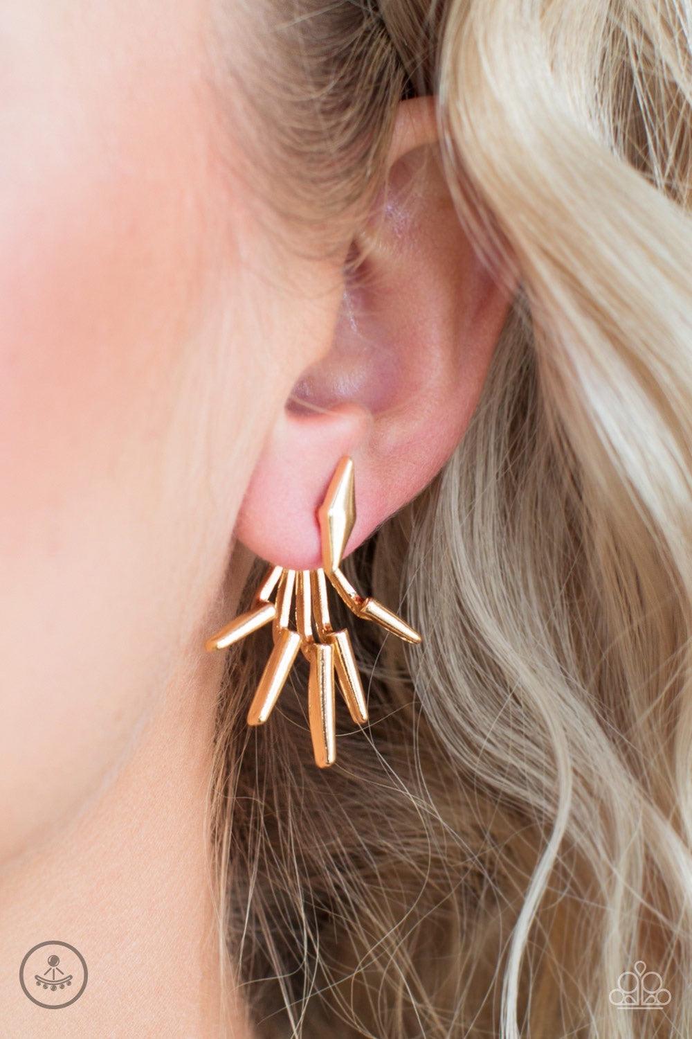 Paparazzi Accessories Extra Electric - Gold A gold diamond-shape frame attaches to a double-sided post, designed to fasten behind the ear. Radiating with matching gold frames, the double-sided post peeks out beneath the ear, creating an edgy fringe. Earri
