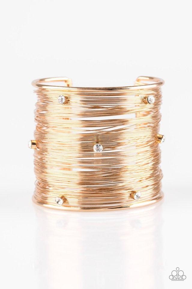 Paparazzi Accessories Professional Prima Donna - Gold Shimmery gold wires wrap back and forth along a gold frame, creating a bold cuff. Glassy white rhinestones are sprinkled across the dramatic cuff for a glamorous finish. Jewelry