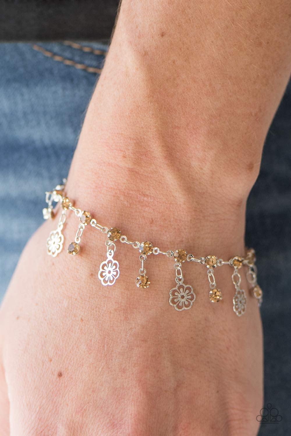 Paparazzi Accessories Hibiscus Breeze - Brown Dainty silver flower charms swing from the wrist in a whimsical fashion. Glittery topaz rhinestones fall between the tropical flowers for a sparkling finish. Features an adjustable clasp closure. Jewelry