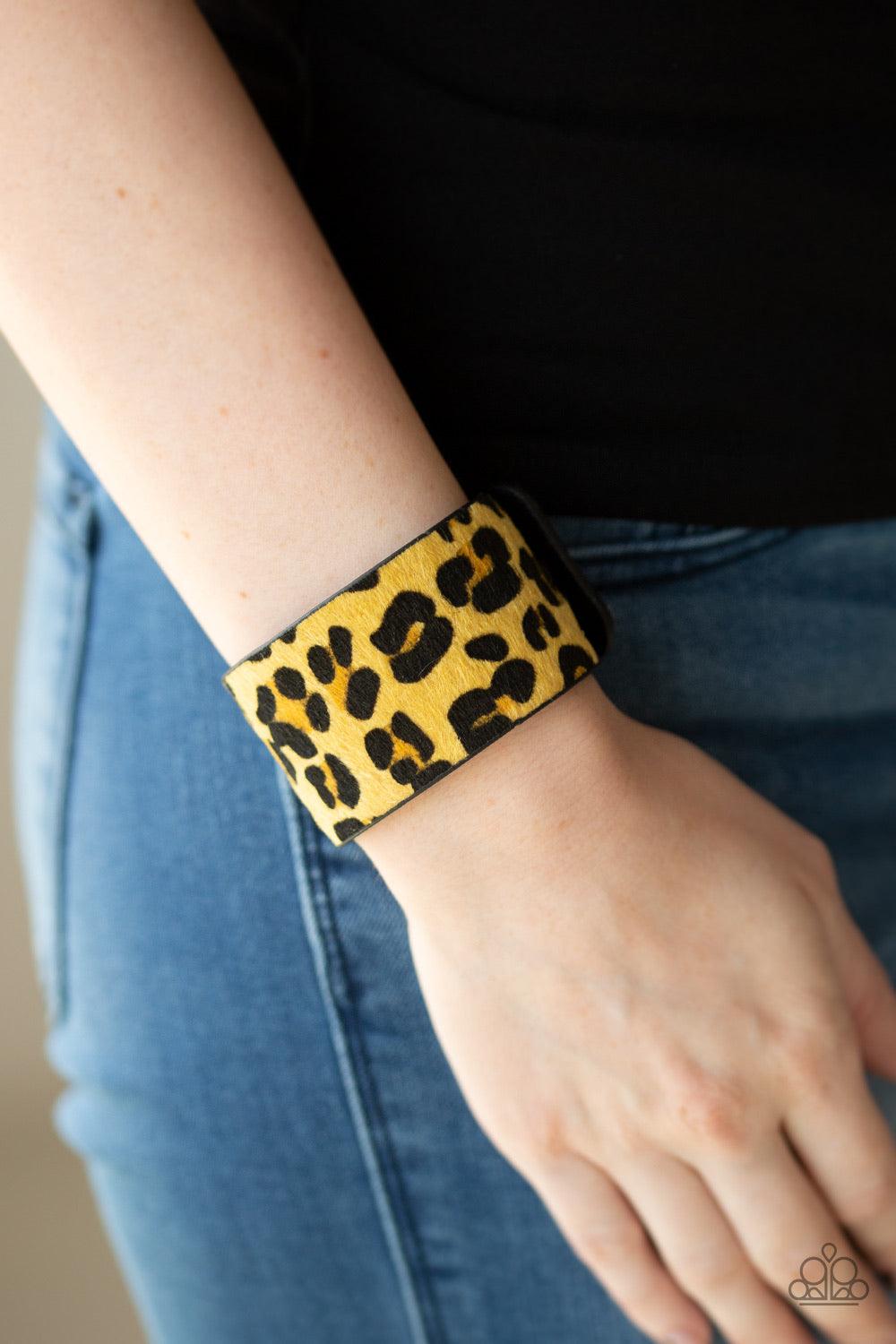 Paparazzi Accessories Cheetah Cabana - Yellow A fuzzy yellow cheetah pattern is printed across the front of a thick black leather band for a wild look. Features an adjustable snap closure. Jewelry