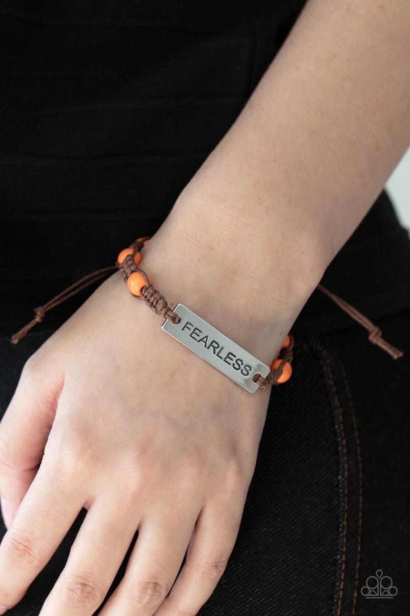 Paparazzi Accessories Conversation Piece - Orange A silver plate engraved with the word "FEARLESS" is centered between brown knotted cording. Accented with bright orange stone beads, it slides around the wrist for an unconventional conversation starter. F