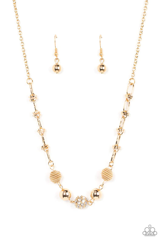 Paparazzi Accessories Taunting Twinkle - Gold Pairs of gold coiled and smooth gold beads flank a white rhinestone encrusted bead along an oval and gold disc linked chain, creating a glitzy combination below the collar. Features an adjustable clasp closure