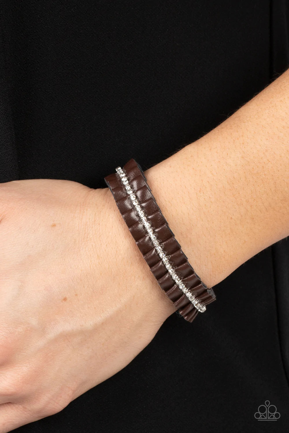 Paparazzi Accessories Pretty, Pretty PLEATS - Brown A brown leather ribbon delicately gathers into pleats around the wrist. A glittery strand of white rhinestones adorns the center of the pleats, adding a glitzy accent to the textured centerpiece. Feature