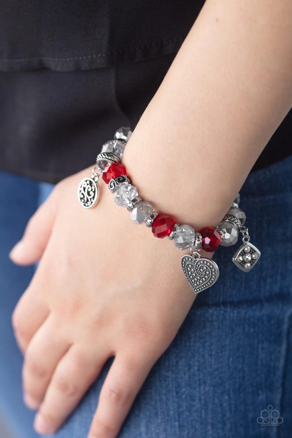 Paparazzi Accessories Fabulously Flirty - Red Dipped in metallic shimmer, smoky crystal-like beads, dainty silver rings, and red crystal-like beads are threaded along a stretchy band around the wrist. Decorative silver heart charms, a white rhinestone enc