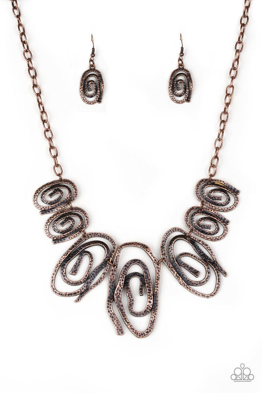 Paparazzi Accessories My Cave is Your Cave - Copper Delicately hammered in shimmery detail, warped copper frames spin into dizzying spirals. Gradually increasing in size near the center, the asymmetrical frames link below the collar for a bold tribal insp