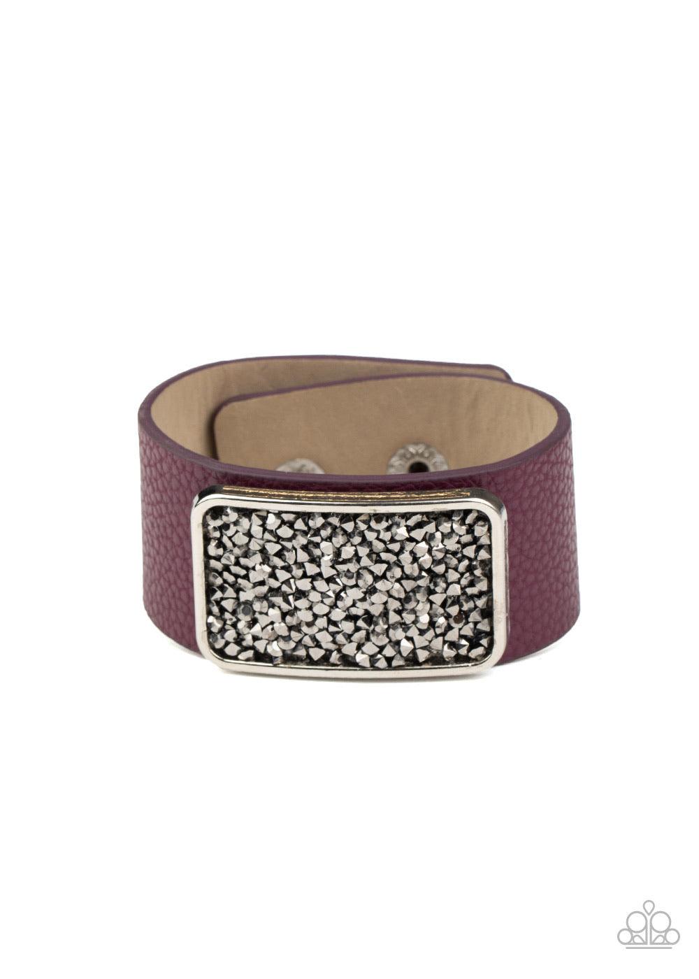 Paparazzi Accessories Interstellar Shimmer - Purple A collision of smoky and hematite rhinestones collect inside a silver rectangular frame that is studded in place in the center of a thick plum leather band, creating a sparkling statement piece around th