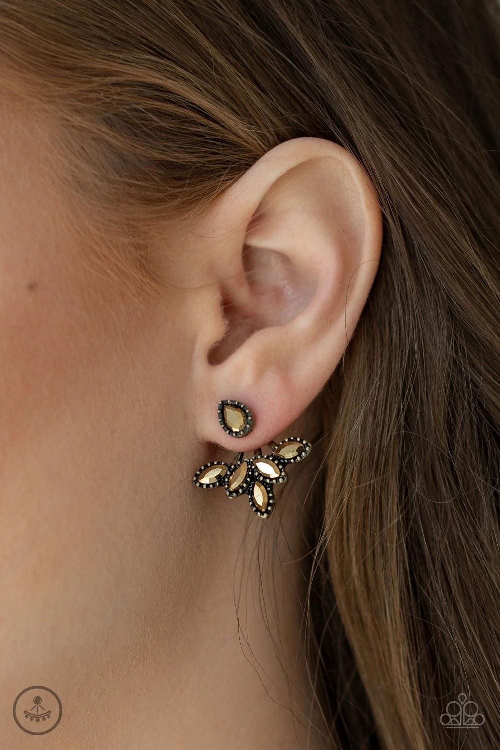 Paparazzi Accessories A Force To BEAM Reckoned With - Brass A solitaire teardrop aurum rhinestone attaches to a double-sided post, designed to fasten behind the ear. Encrusted in matching aurum rhinestones, a double-sided post peeks out beneath the ear, c