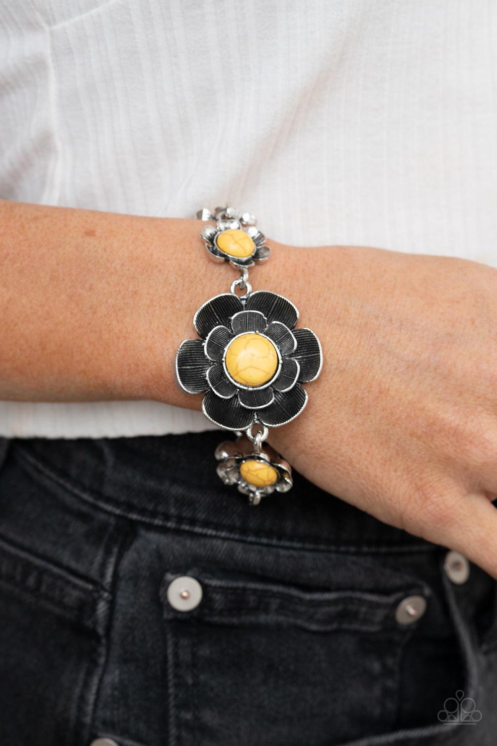 Paparazzi Accessories Badlands Blossom - Yellow Layers of lifelike silver petals bloom from sunny yellow centers, creating gorgeous floral fittings that wrap around the wrist. The frames vary in size, with the largest flower sitting at the center of the d