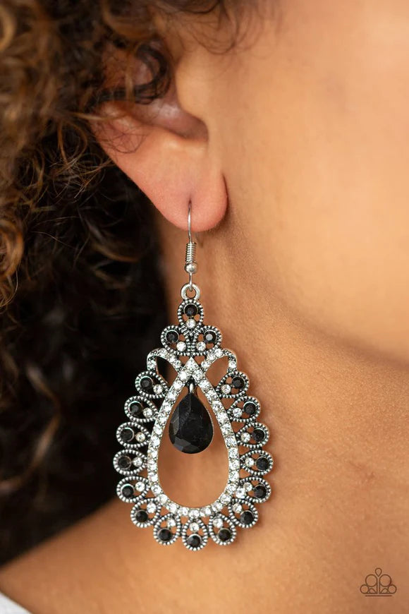 Paparazzi Accessories All About Business - Black A black teardrop gem swings from the top of a frilly silver frame radiating with glassy white and glittery black rhinestone encrusted petals for a regal look. Earring attaches to a standard fishhook fitting