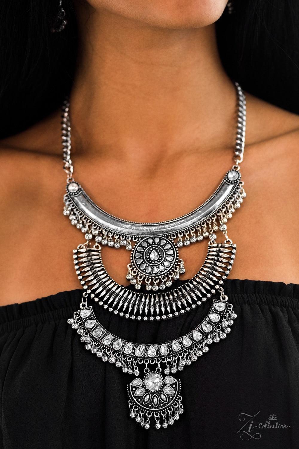 Paparazzi Accessories Legend Three oversized crescent plates connect vertically down the chest, creating a dramatically stacked pendant. Infused with shimmery tribal patterns and layers of flirty beaded fringe, glittery white rhinestones are haphazardly p