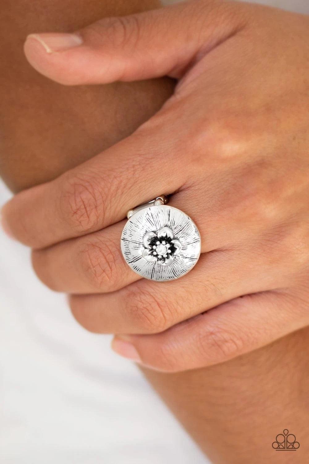 Paparazzi Accessories Blooming Beach Party - White Dotted with a sparkling white rhinestone, a dainty silver flower blooms atop a rounded frame radiating with shimmery silver texture for a seasonal look. Features a stretchy band for a flexible fit. Sold a