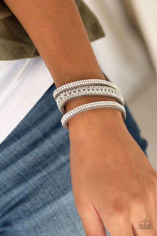 Paparazzi Accessories Rollin’ In Rhinestones - Silver Rows of glassy white rhinestones and a shimmery silver chain are encrusted along gray suede bands for a sassy look. Features an adjustable snap closure. Jewelry