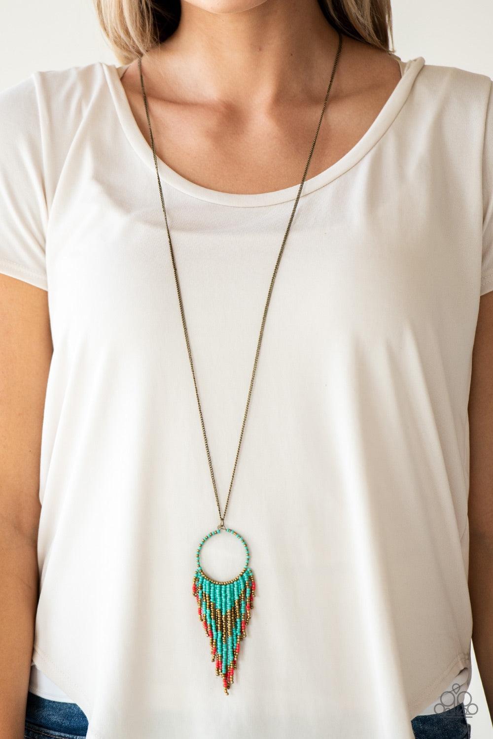 Paparazzi Accessories Badlands Beauty - Blue Infused with blue, brass, and red seed beads, a colorful dream catcher like pendant swings from the bottom of a lengthened brass chain for a tribal inspired look. Features an adjustable clasp closure. Jewelry
