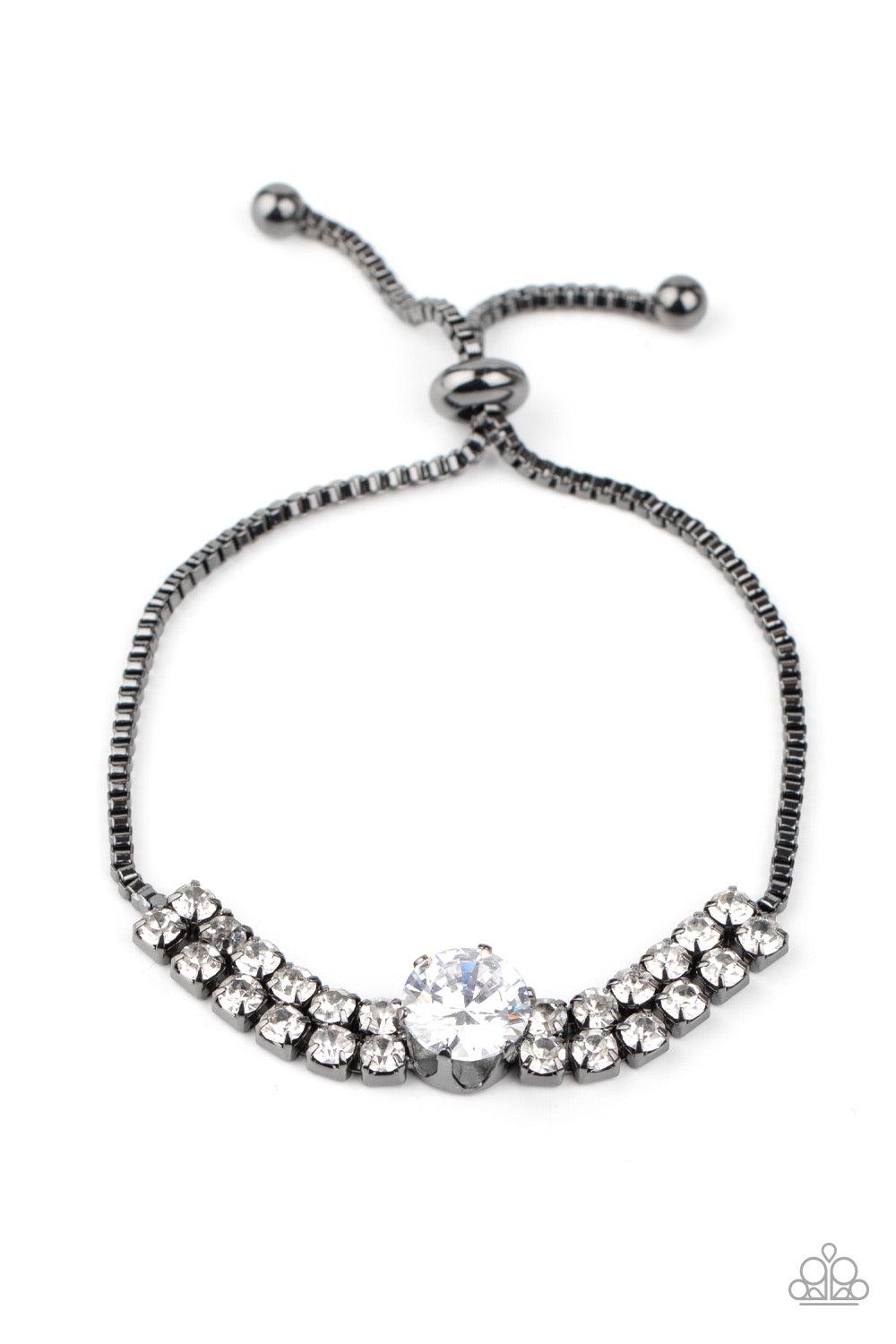 Paparazzi Accessories Gorgeously Glitzy - Black An oversized white rhinestone dots the center of two rows of glittery white rhinestones that attach to a dainty strand of gunmetal box chain around the wrist for a glamorous finish. Features an adjustable sl
