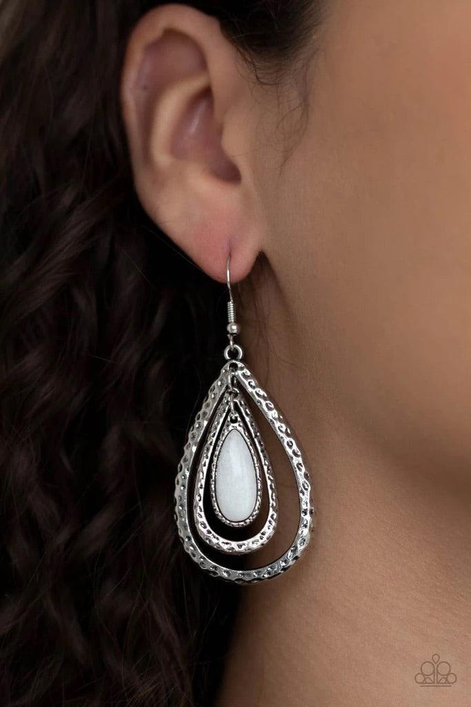 Paparazzi Accessories Teardrop Torrent - White A white teardrop stone swings from the top of a hammered silver frame that links to a larger hammered silver frame, creating a rippling lure. Earring attaches to a standard fishhook fitting. Sold as one pair