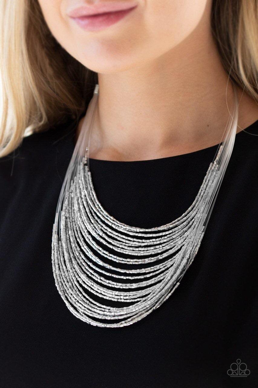 Paparazzi Accessories Catwalk Queen - Silver Strand after strand of metallic silver seed beads fall together to create a bold statement piece. Features an adjustable clasp closure.Sold as one individual necklace. Includes one pair of matching earrings. Je