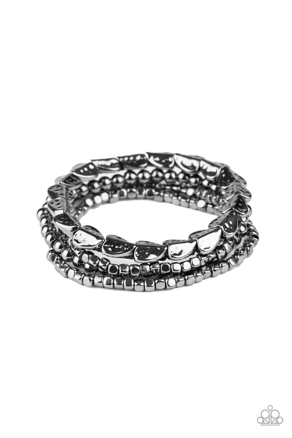 Paparazzi Accessories Ancient Heirloom - Black A collection of gunmetal cubes, classic gunmetal beads, and hammered spade-like beading is threaded along stretchy bands around the wrist for a boldly stacked look. Jewelry