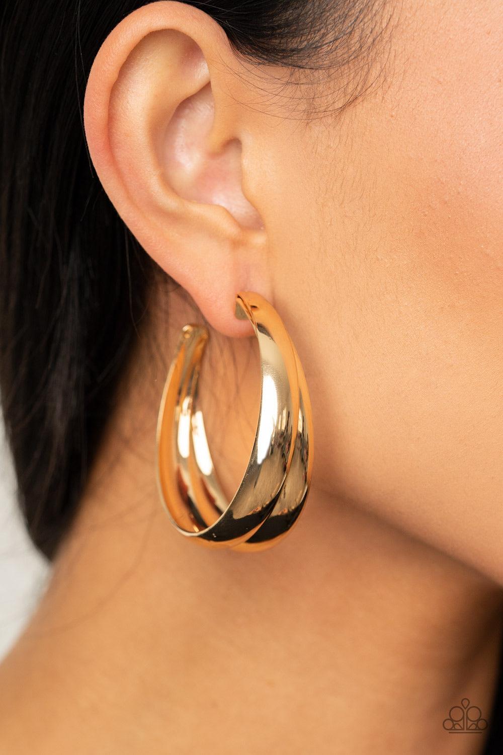 Paparazzi Accessories Colossal Curves - Gold Two thick gold bars delicately overlap into a boldly oversized hoop. Earring attaches to a standard post fitting. Hoop measures approximately 2" in diameter. Sold as one pair of hoop earrings. Jewelry