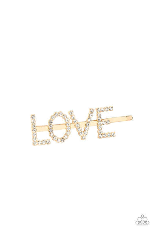 Paparazzi Accessories All You Need is Love - Gold Encrusted in glassy white rhinestones, glistening gold letters spell out the word, "LOVE," across the front of a gold bobby pin for a lovable look. Sold as one individual hair clip. Hair Accessories